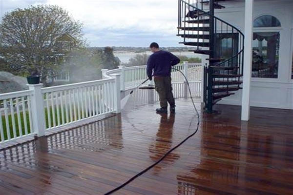 Man pressure washing a wood deck.