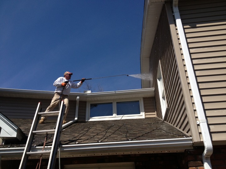 man pressure washing on roof